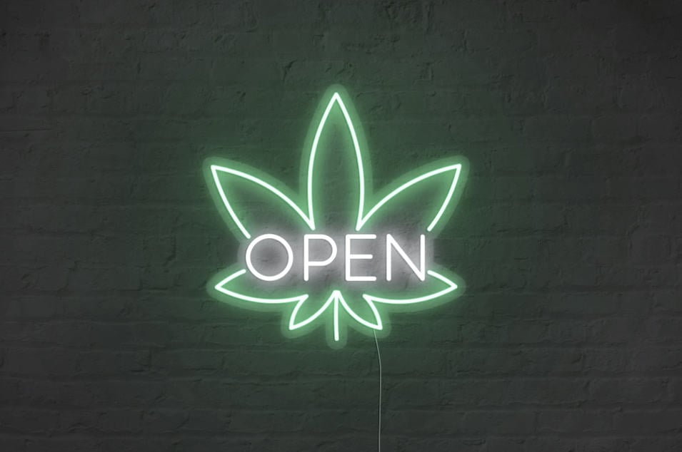 Neon 'open' sign in the shape of a cannabis leaf, symbolising a head shop.